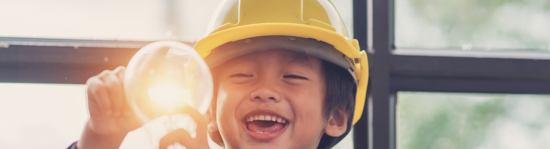 Enfant souriant qui tient une ampoule